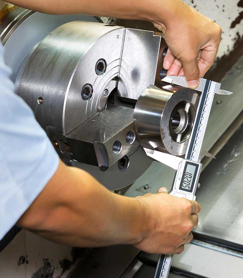 Tychon machinist measuring work at a lathe